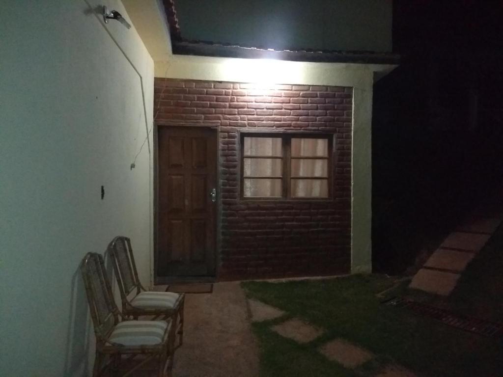 a room with chairs and a door and a brick wall at Suíte com cozinha em Ibitipoca in Conceição da Ibitipoca