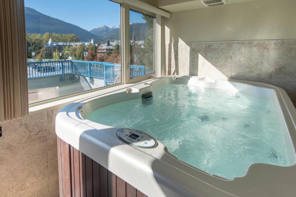 a bath tub in a room with a large window at Village Gate House by Whiski Jack in Whistler