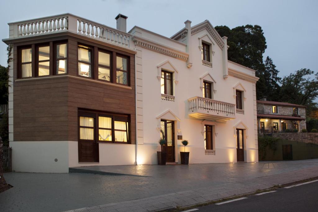 una gran casa blanca con muchas ventanas en Complejo Turístico Rural A TORRE DE LAXE en Laxe