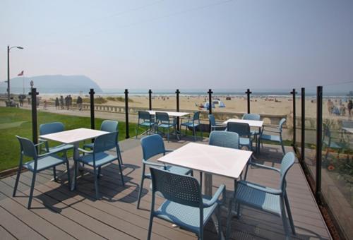 a deck with tables and chairs and the beach at Seashore Inn on the Beach Seaside in Seaside