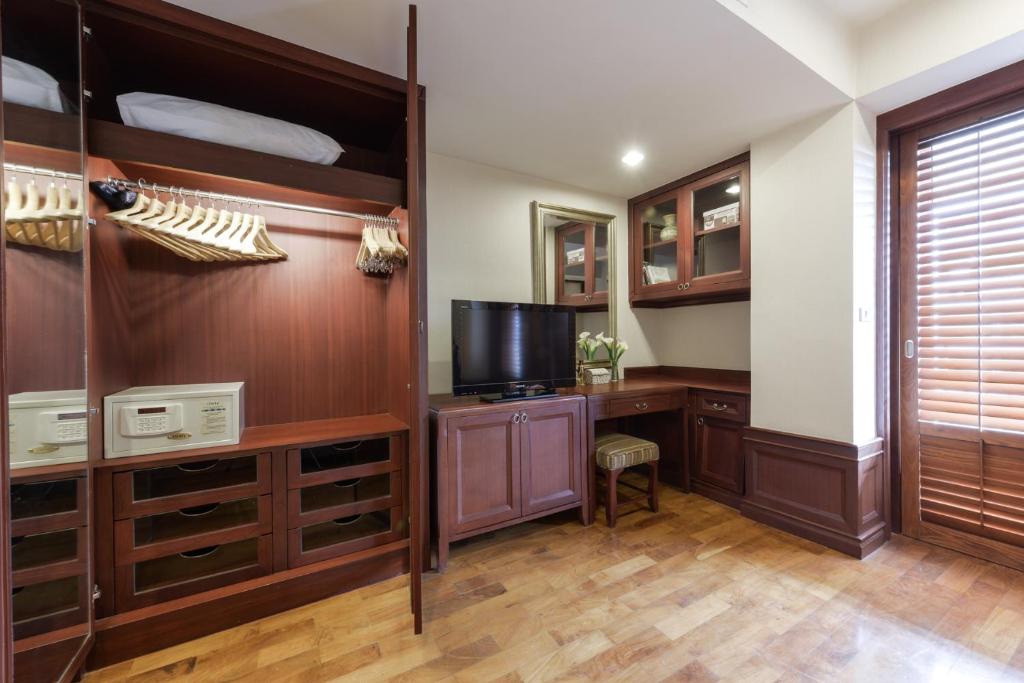 A bedroom corner with an open wardrobe, safe, television and built-in writing desk.