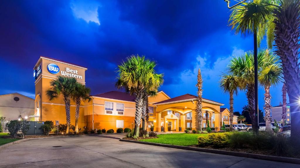 a hotel with palm trees in front of a building at Best Western Lafayette Inn in Lafayette