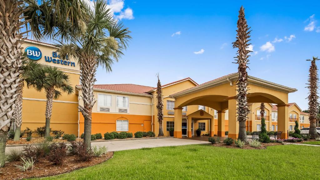 a hotel with palm trees in front of a building at Best Western Lafayette Inn in Lafayette