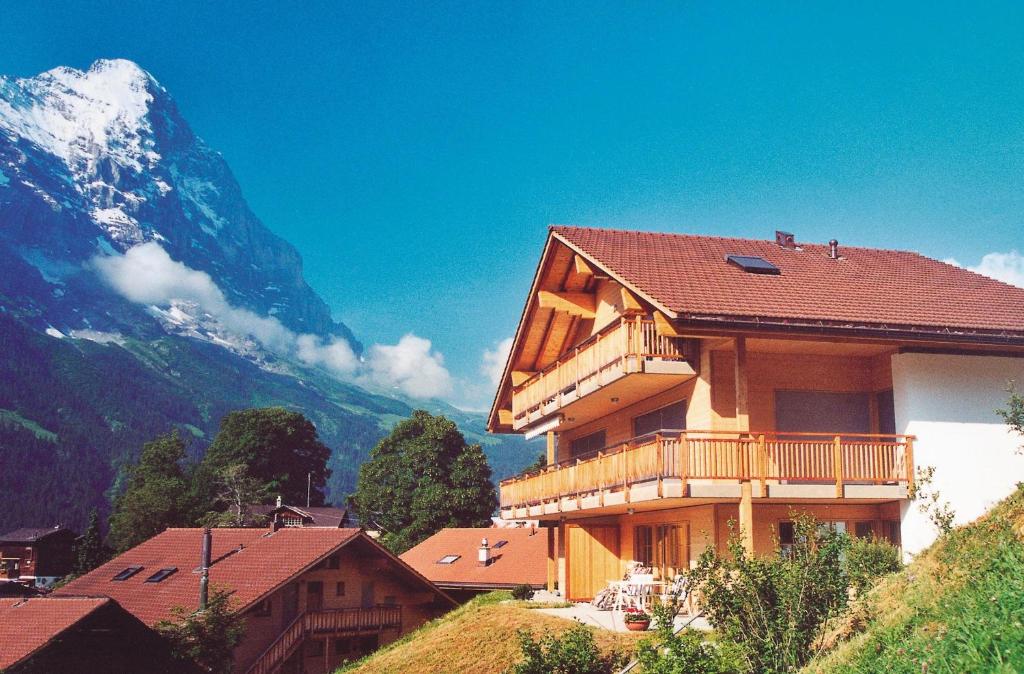un bâtiment sur une colline avec une montagne en arrière-plan dans l'établissement Serviced Apartments – Kirchbühl@home, à Grindelwald