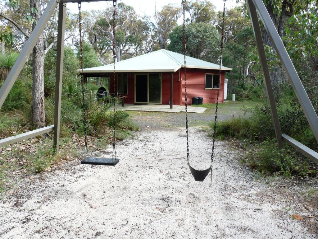a swing in front of a small red house at Wrenwood Chalets in Augusta