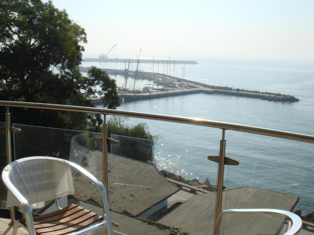 una silla blanca sentada en un balcón con vistas al agua en Balchik English House, en Balchik