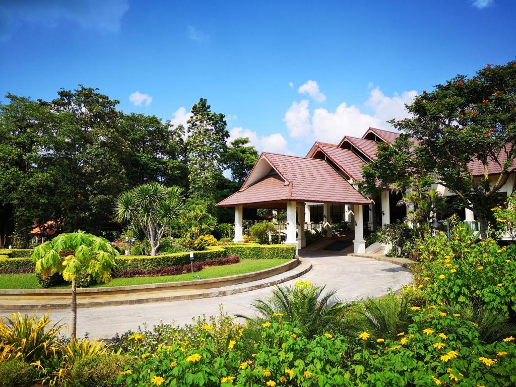 a house with a garden with flowers and trees at Aekpailin River Kwai Resort in Kanchanaburi City