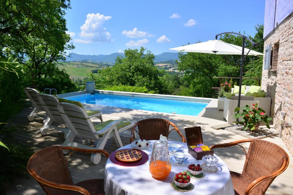 een tafel met eten en drinken op een patio met een zwembad bij villa la chiesetta - private pool in Fabriano