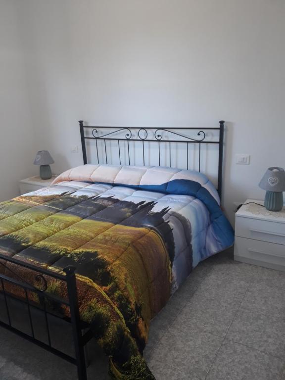 Un dormitorio con una cama con una manta. en Carso, en Alberese