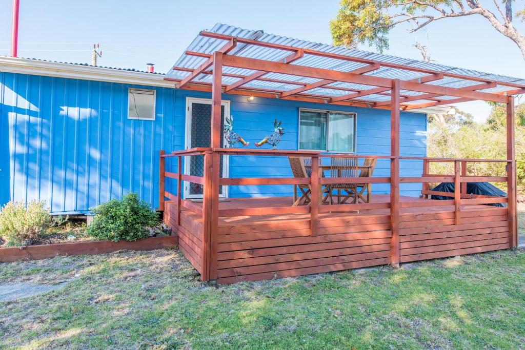 a deck with a pergola and a blue house at Miramar Cottage in Denmark