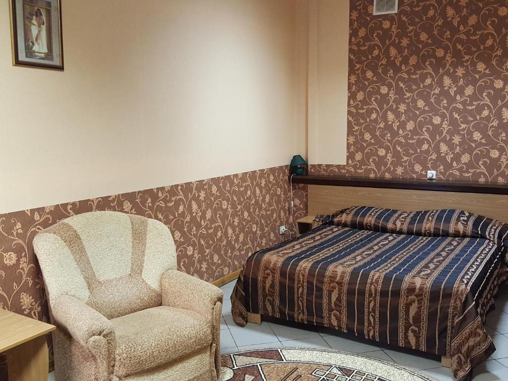 - une chambre avec un lit et une chaise à côté d'un lit dans l'établissement Hotel Pribrezhnaya, à Kalouga