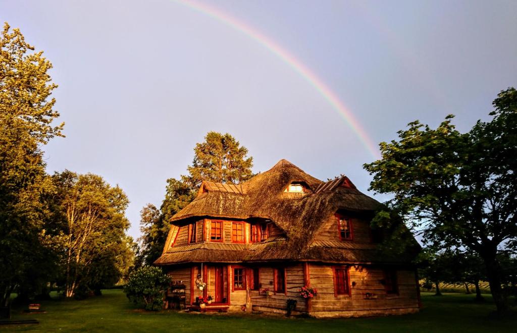 una casa vieja con un arco iris en el fondo en Toomalõuka Tourist Farm, en Toomalõuka