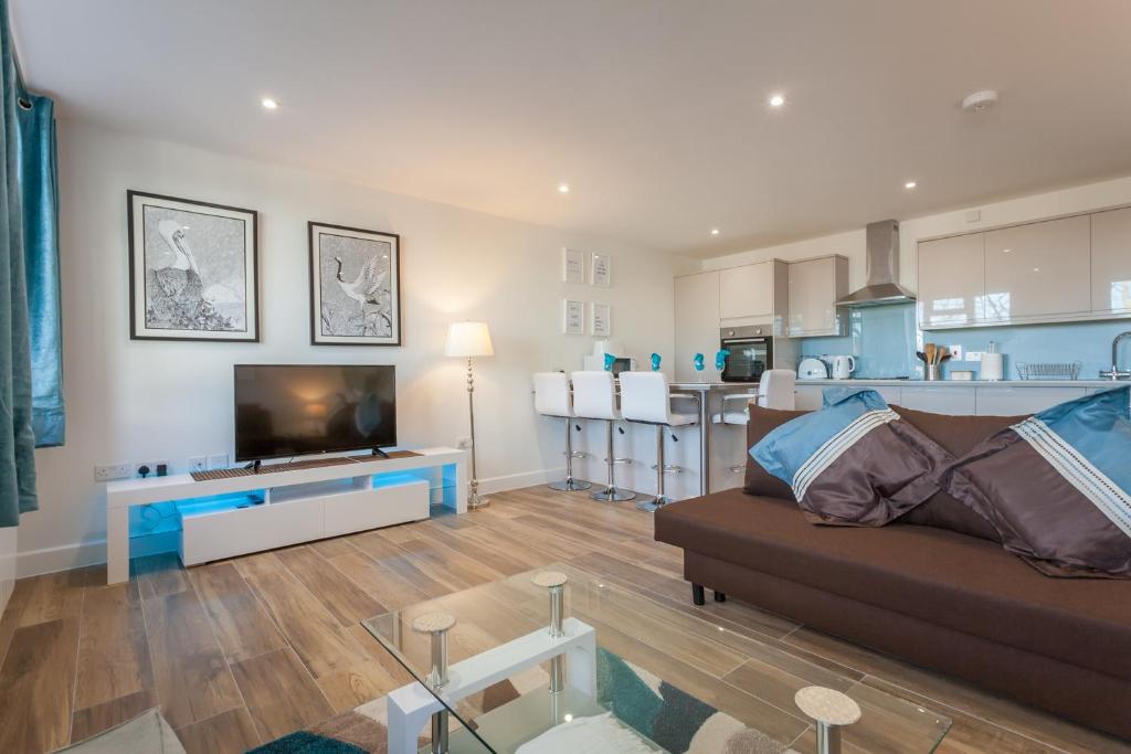 ein Wohnzimmer mit einem Sofa und einer Küche in der Unterkunft Treetops Apartment in Milton Keynes