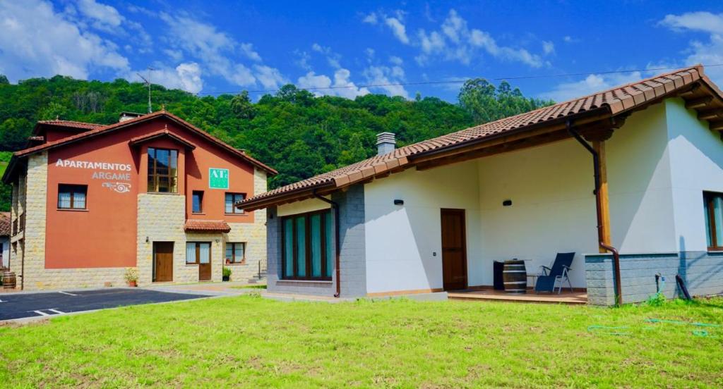 un grupo de edificios en un campo con árboles en el fondo en Apartamentos Rurales Argame, en Argamé