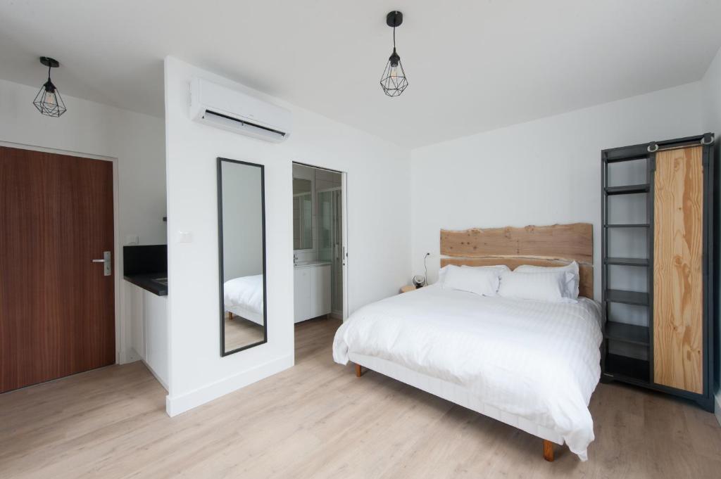 a bedroom with a large white bed and a mirror at Le Jardin d Ambroise in Saint-Priest-en-Jarez