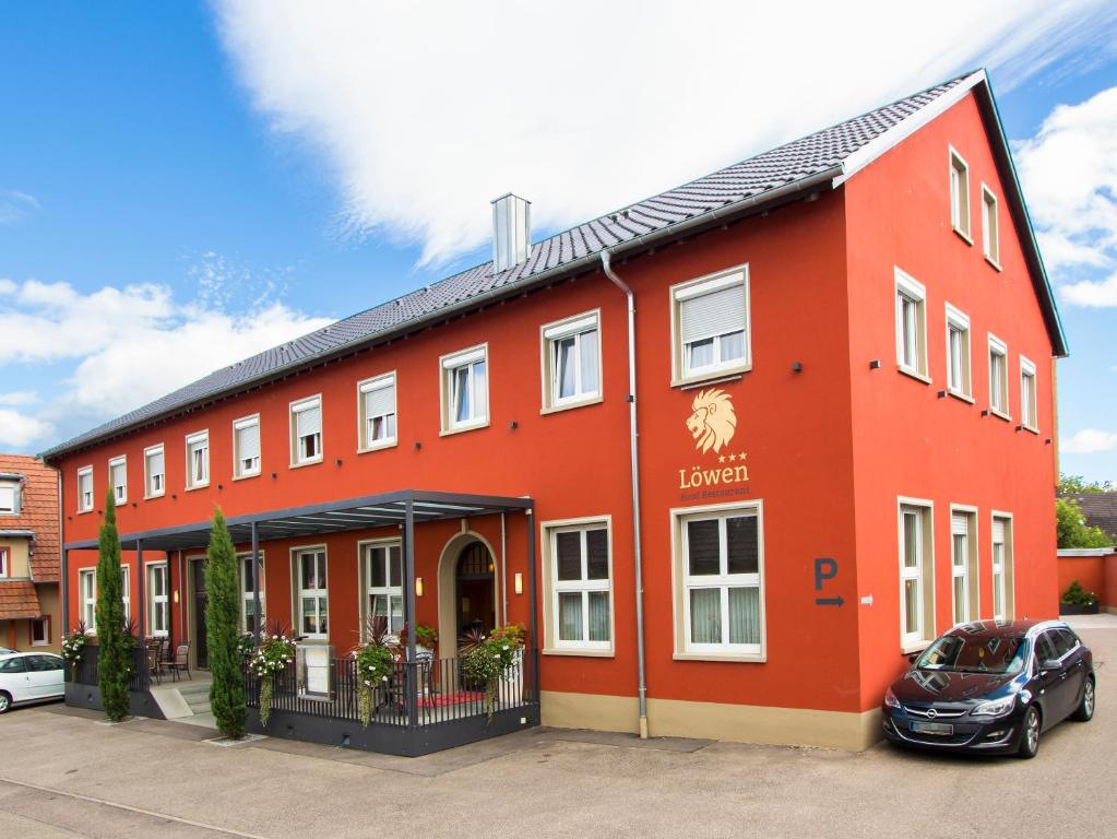 a red building with a car parked in front of it at Hotel Löwen Garni - B&B in Rust