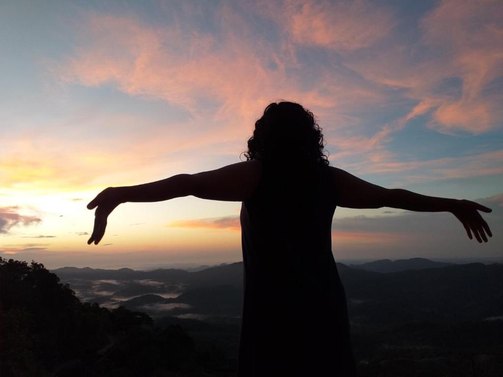 a woman standing on top of a mountain with her arms outstretched at ARROW Haputale village inn in Haputale