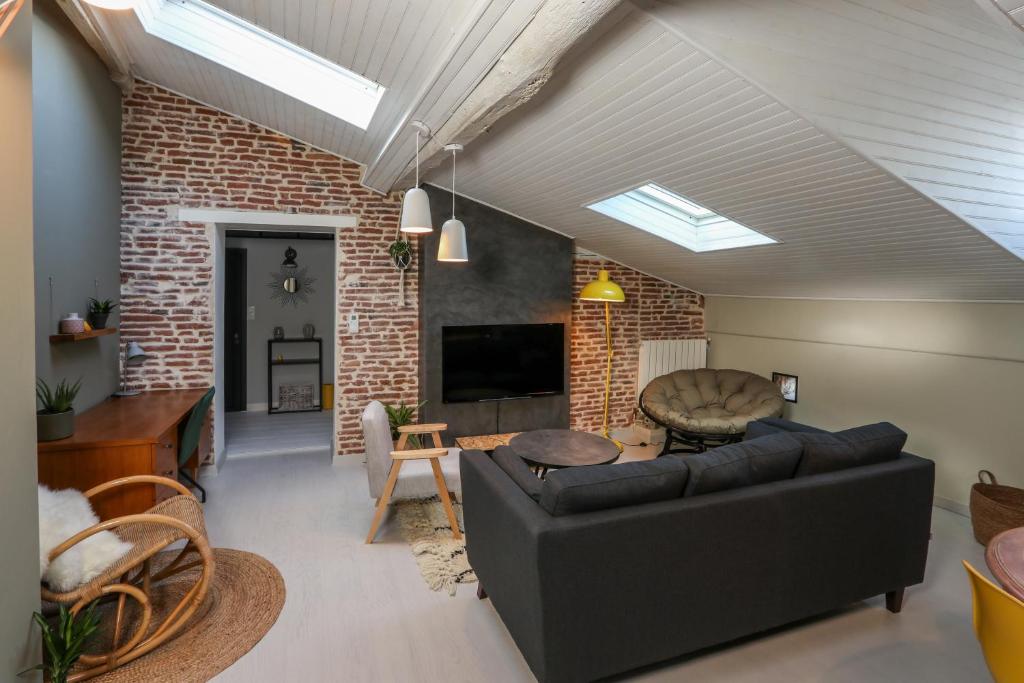 a living room with a couch and a brick wall at 6 Rue d'Aubuisson in Toulouse
