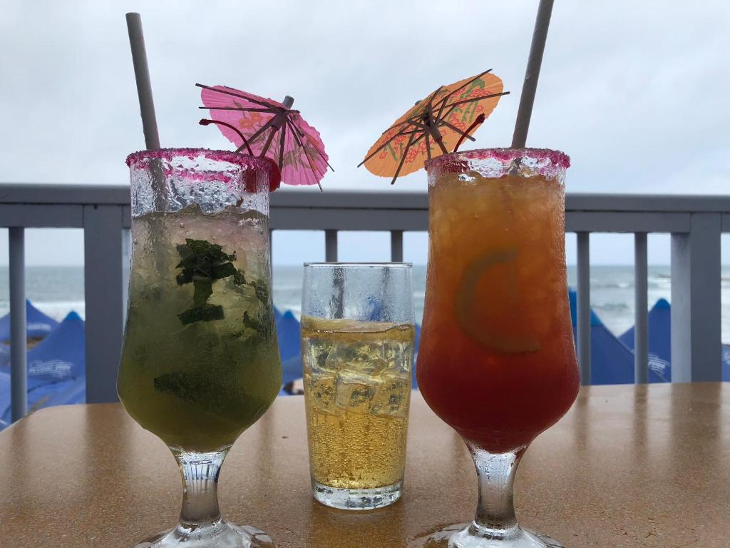 three drinks sitting on a table on a balcony at Sea-View Nautica @ Mossel Bay in Mossel Bay