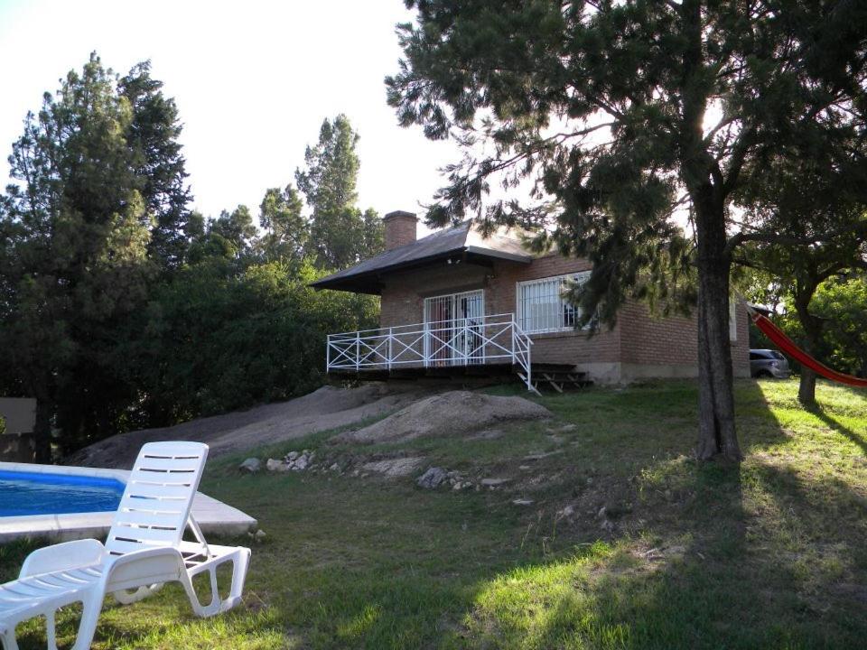 ein Haus mit einem Pool und zwei Stühlen davor in der Unterkunft Casa en Playa Perelli in Villa Carlos Paz