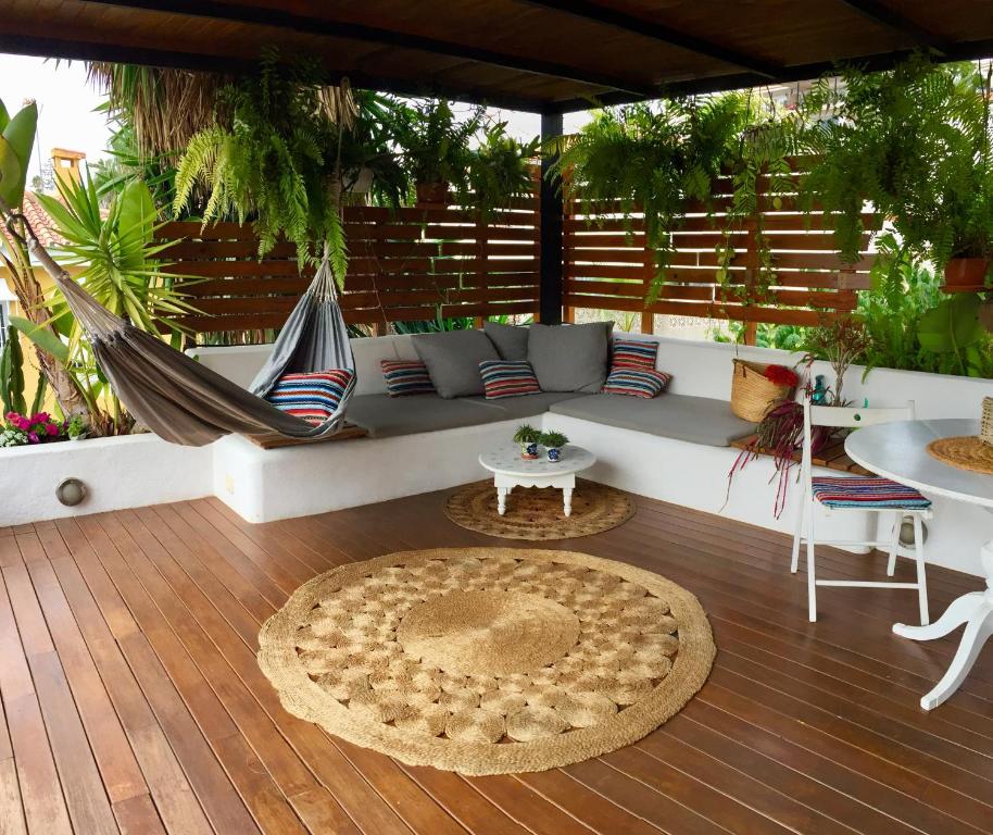 un patio con hamaca, mesa y sillas en CUBO DE MADERA individual con Jardín y Porche en Torre de Benagalbón