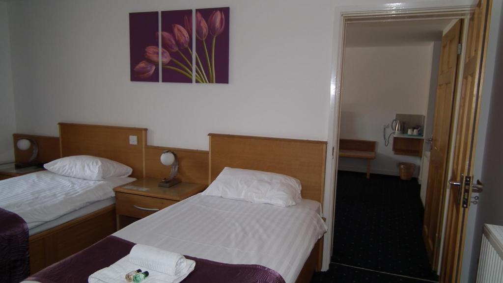 a hotel room with two beds and a mirror at The Beach Motel in Trearddur