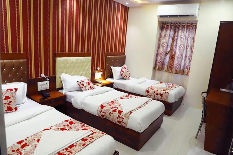 a hotel room with three beds with red walls at Hotel Golden Hayyath Inn in Mumbai