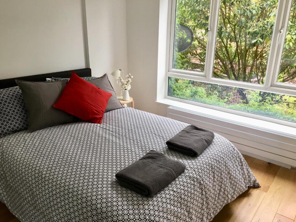 ロンドンにあるPerfect Modern Base Near All Attractionsの窓の前に枕2つが付いたベッド