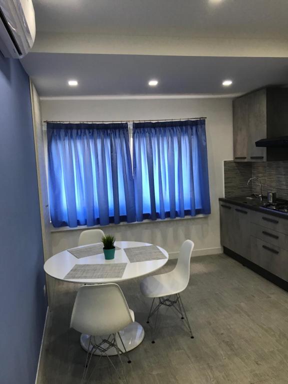 ナポリにあるMarina Guest Homeのキッチン(テーブル、椅子付)、青い窓が備わります。