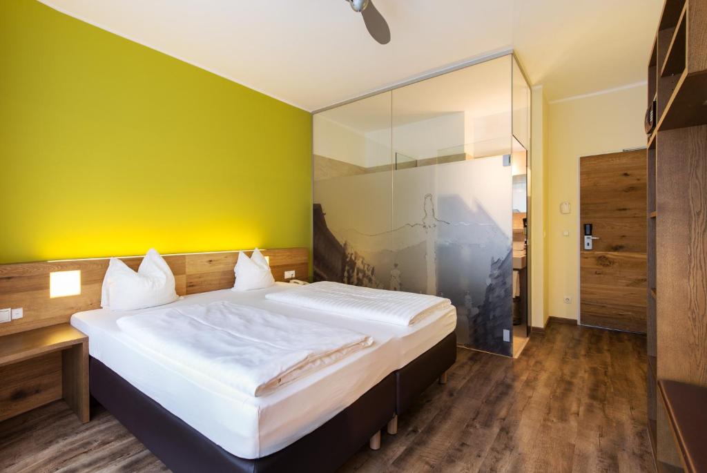 um quarto com uma cama grande e uma parede amarela em Basic Hotel Innsbruck em Innsbruck