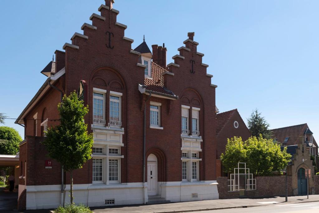 a large red brick building on a street at LOGIS - Belle Hôtel, Lille-Ouest in Bailleul
