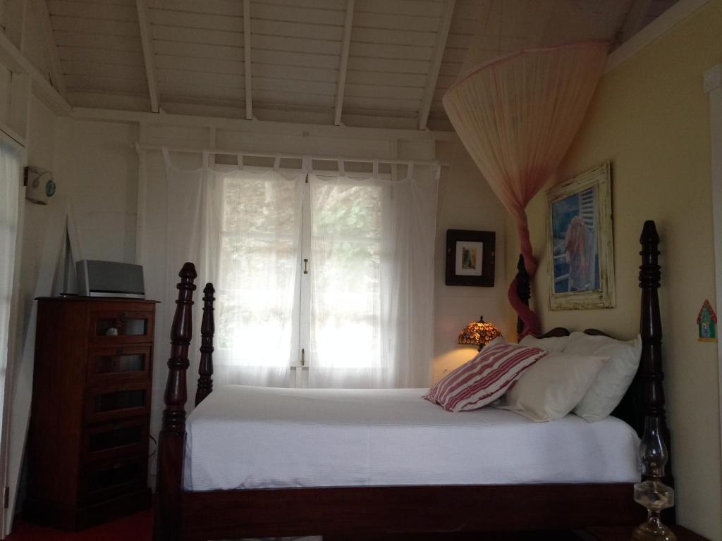 a bedroom with a bed and a window at Calabash Cottage in Five Islands Village