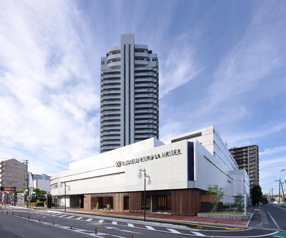 a large white building with a clock on the side of it at Kusatsu Estopia Hotel in Kusatsu