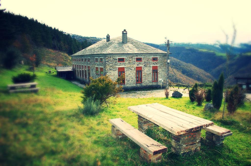 ein großes Steinhaus mit einer Bank davor in der Unterkunft Elteixorural in Teijois