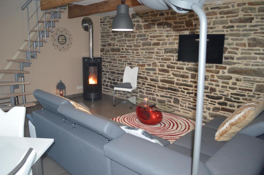 a living room with a blue couch and a brick wall at Gîte de L'Hotel Mahey in Champrépus