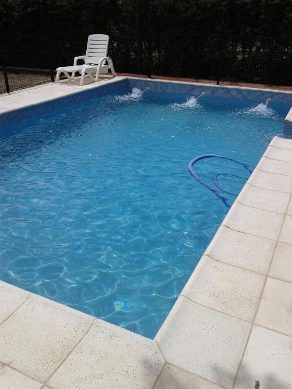 una piscina con una silla y una manguera. en Cabaña Jofra en San Rafael