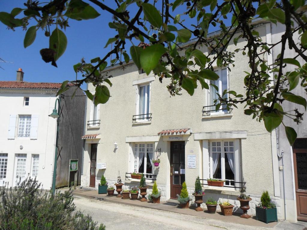 a white building with potted plants on a street at Chambres d'Hôtes Bienvenue in LʼAbsie