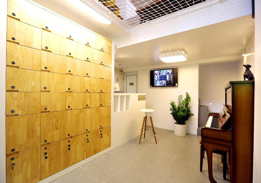 ハノイにあるHanoi Banana Hostelの木製のドアとピアノの大きな壁が備わる客室です。