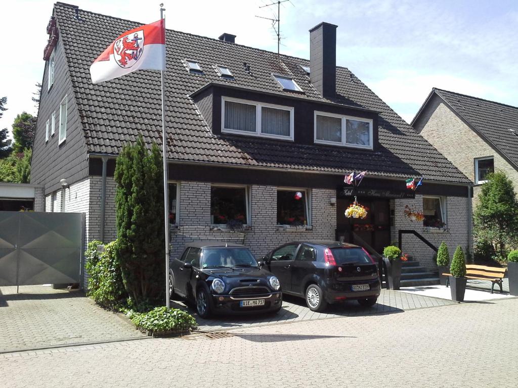 two cars parked in front of a house with a flag at Haus Mariandl in Düsseldorf