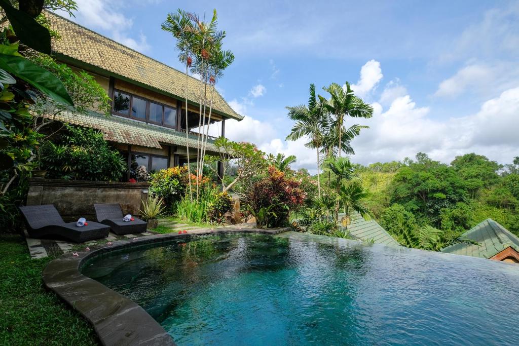 a villa with a swimming pool in front of a house at Sunrise Villa Ubud in Ubud