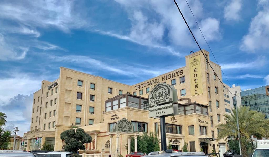 a large building with a sign in front of it at Thousand Nights Hotel Amman - فندق ثاوزند نايتس عمان in Amman