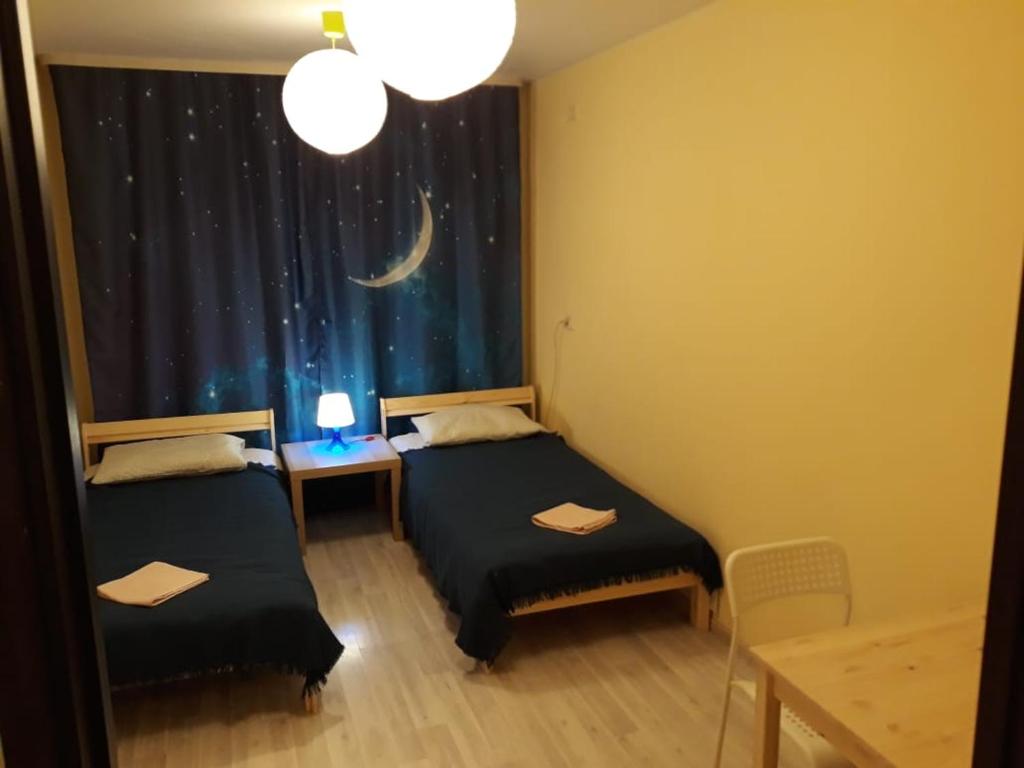 two beds in a room with a window with a moon at SPACE Aparts and Rooms in Yekaterinburg