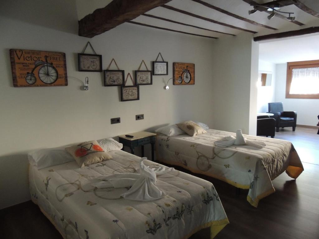 a bedroom with two beds and a table and a chair at Hotel La Huella Del Camino in Belorado
