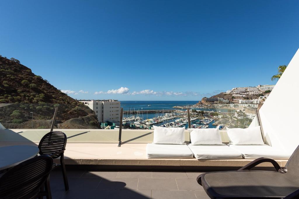 a white couch sitting on a balcony overlooking the ocean at Holiday Club Puerto Calma in Puerto Rico de Gran Canaria