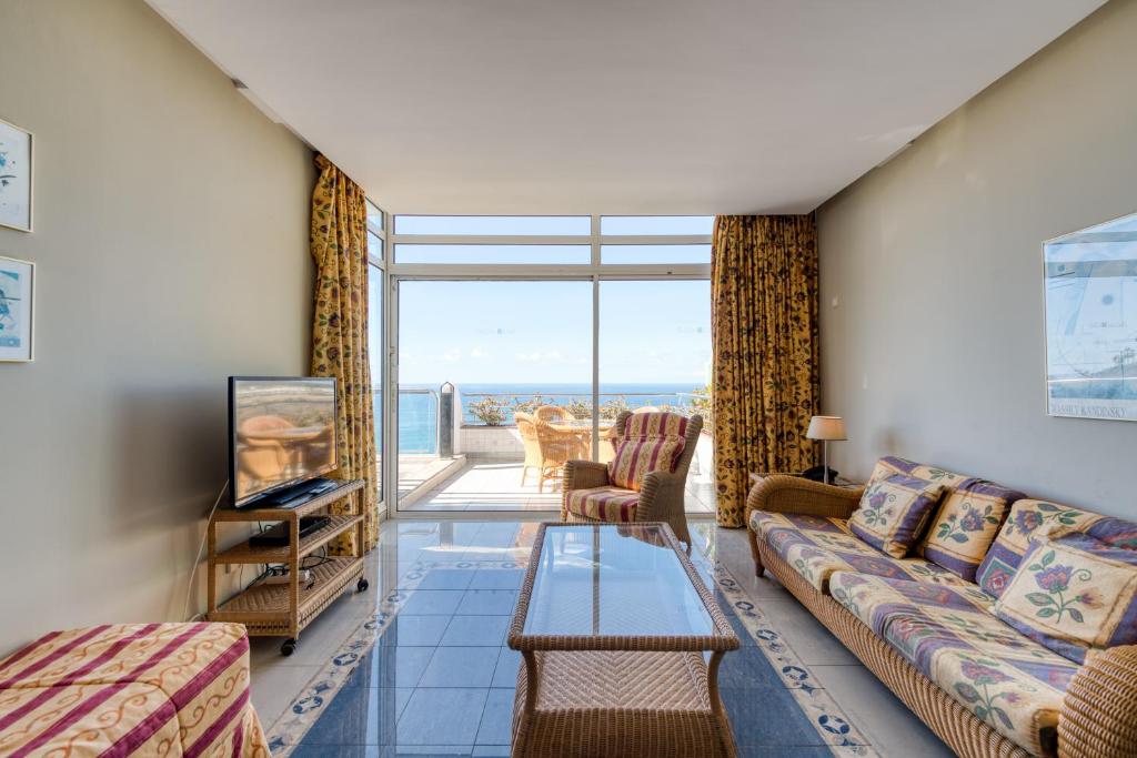 a living room with a couch and a tv at Holiday Club Jardin Amadores in Amadores