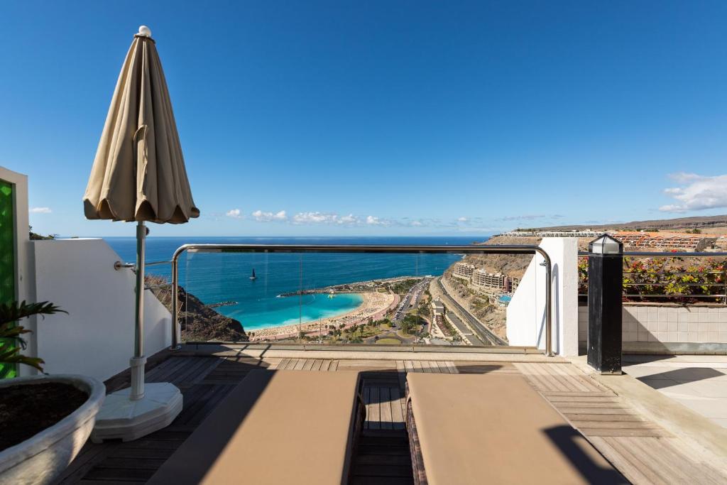 a balcony with an umbrella and a view of the ocean at Holiday Club Jardin Amadores in Amadores