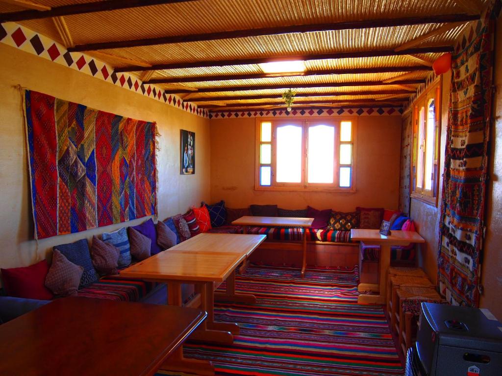 una habitación con sofás, mesas y una ventana en Riad Al Anwar en Tinerhir