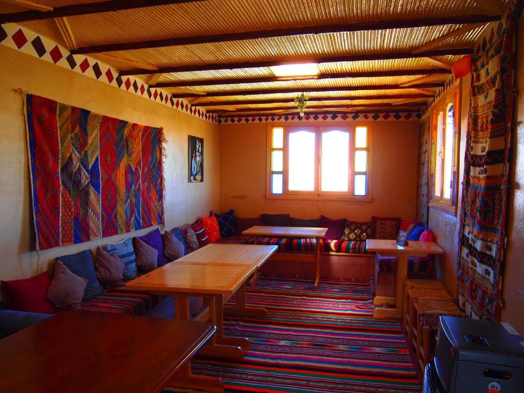 a room with couches and tables and a window at Riad Al Anwar in Tinerhir