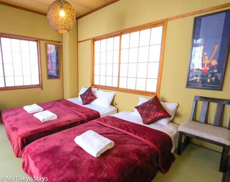 Habitación con 2 camas, silla y ventanas. en 和宿 湯沢チャオ Wayado Yuzawa Ciao, en Yuzawa