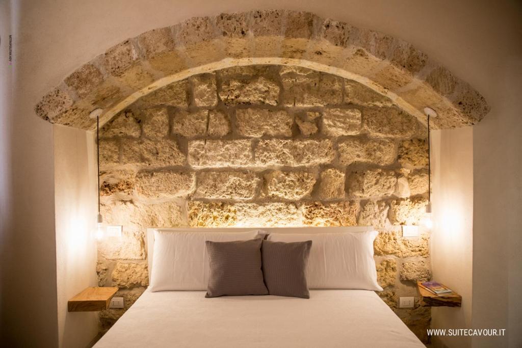 - un lit en face d'un mur en pierre dans l'établissement Suite Cavour B&B, à Galatina